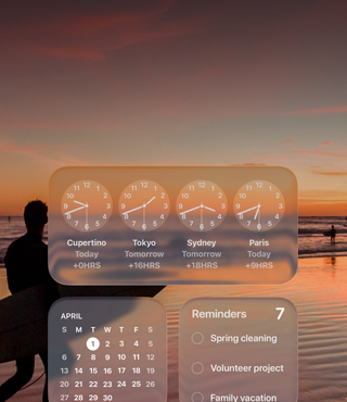 Liquid Glass-widgets Klok, Agenda, Herinneringen en Weer op een macOS Tahoe-scherm op een afbeelding van een surfer die bij zonsondergang op het strand loopt
